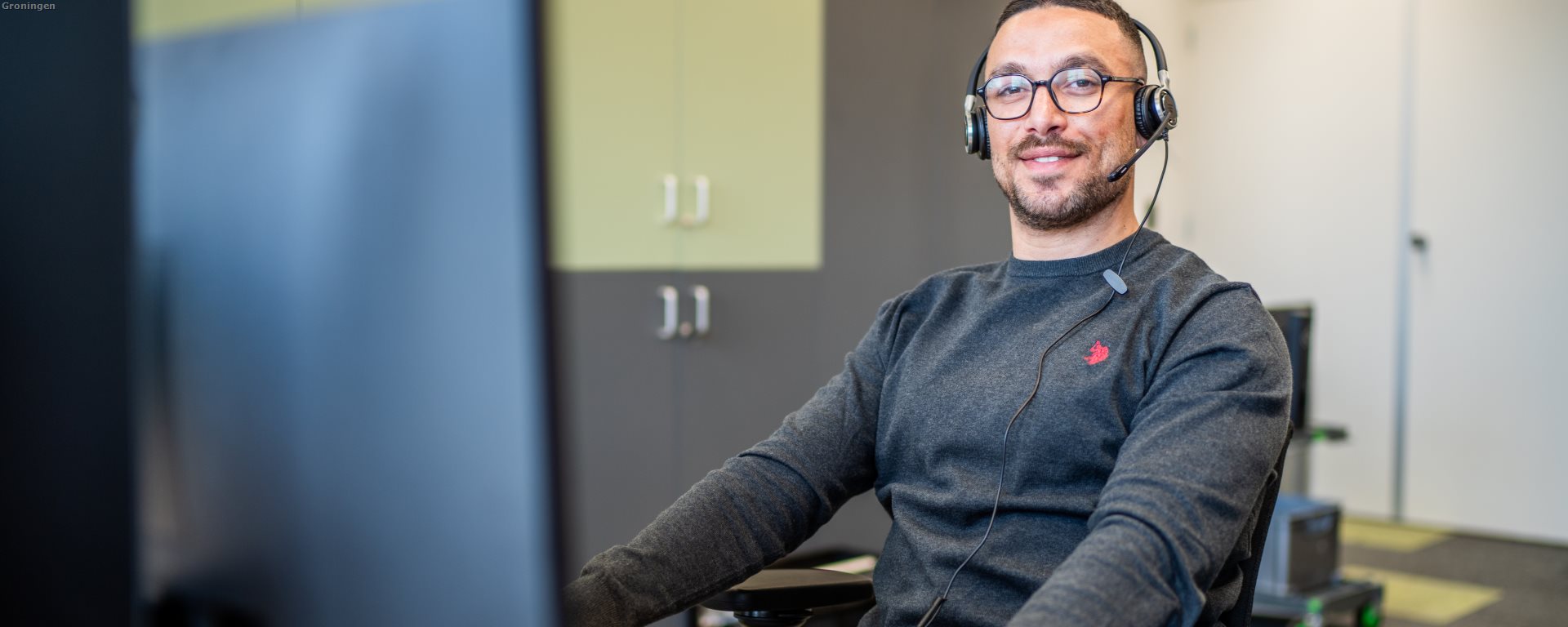 Diverse man achter pc met headset
