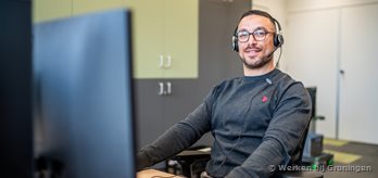 Diverse man achter pc met headset