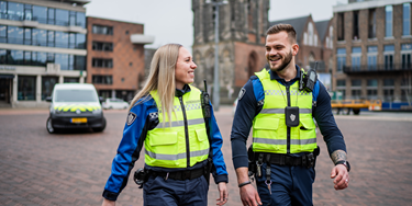 Twee vrolijke BOA-medewerkers lopend over het plein