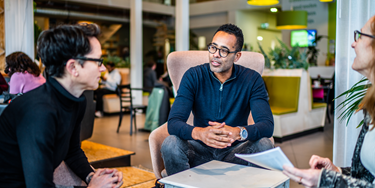 Drie collegas met elkaar in overleg in de lounge