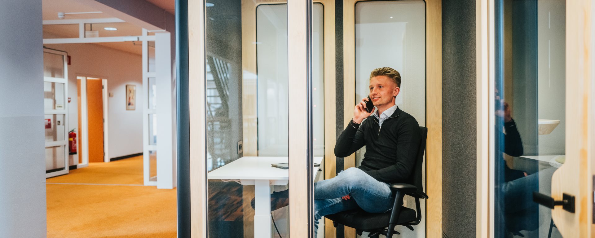 Een medewerker aan de telefoon zittend in een busypod