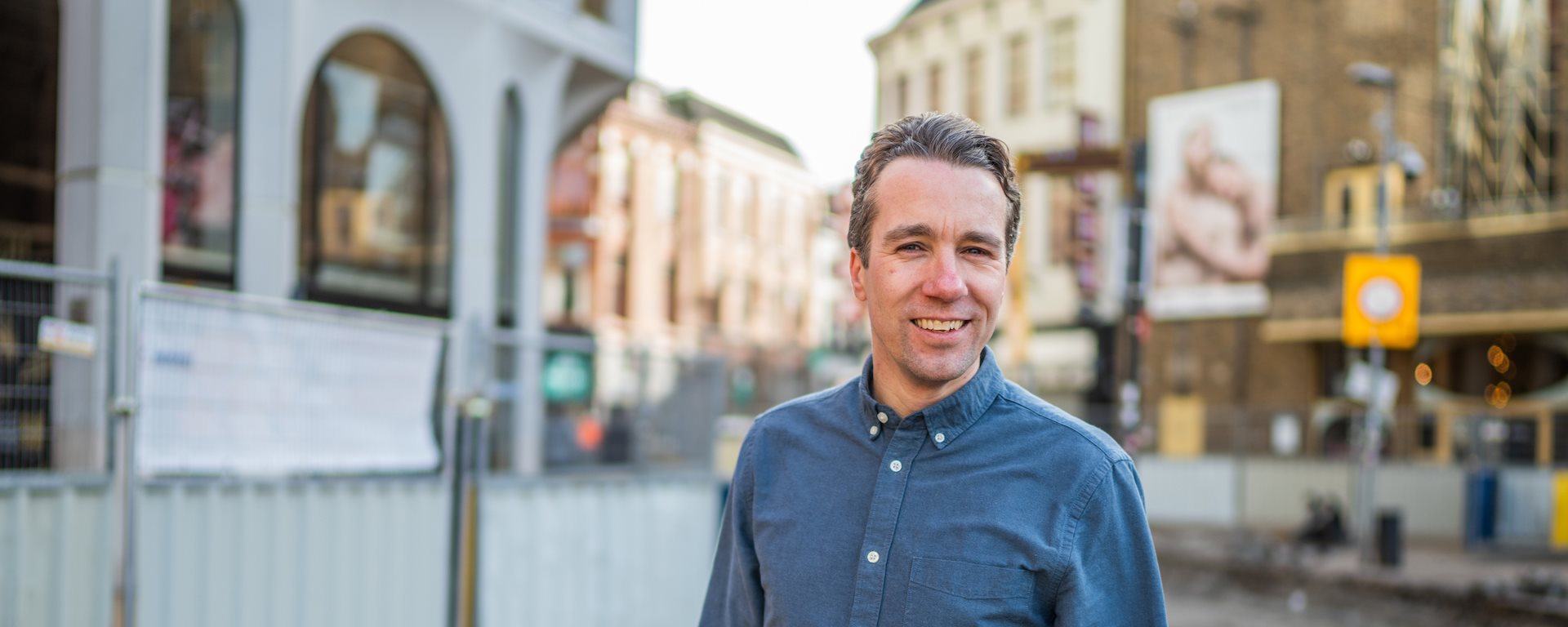 Medewerker Erwin op de Grote Markt met bouwhekken op de achtergrond