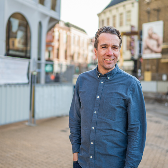 Medewerker Erwin op de Grote Markt met bouwhekken op de achtergrond