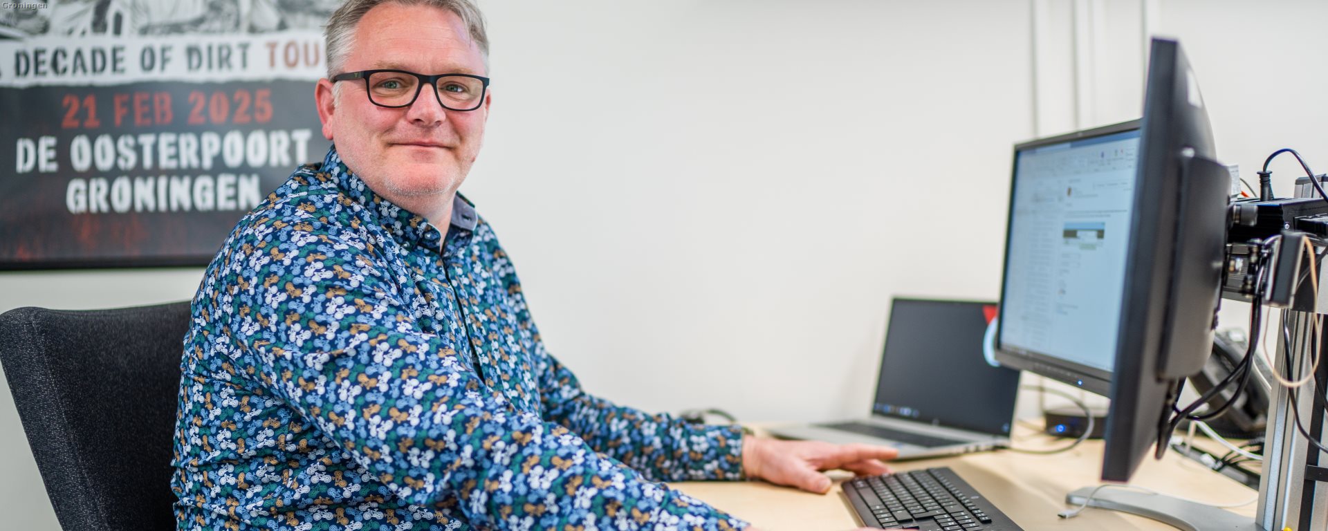 Man achter PC met schermen