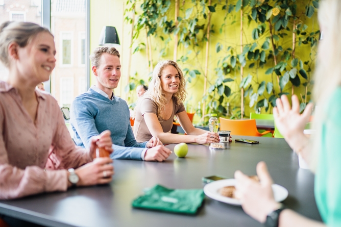 Drie medewerkers op een rij aan een lunchtafel