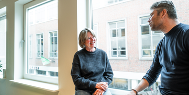 Twee medewerkers leunend bij het raam in gesprek