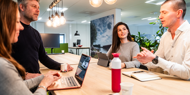Vier medewerkers in overleg aan tafel