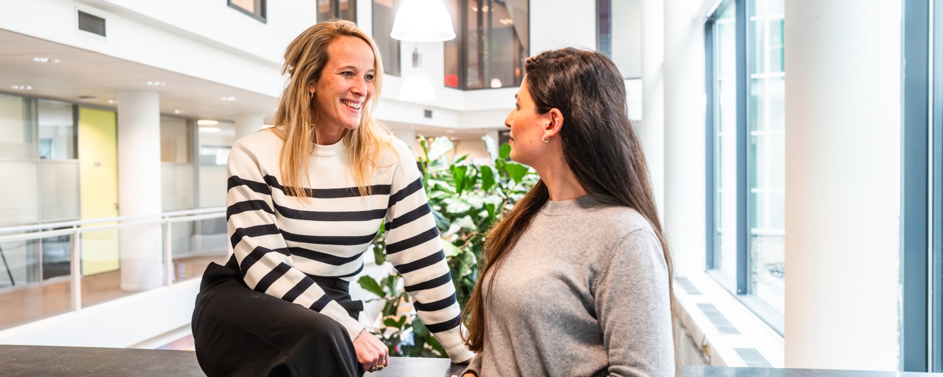 Twee collegas met elkaar in gesprek in de hal (2)