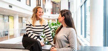 Twee collegas met elkaar in gesprek in de hal (2)