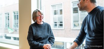 Twee collegas met elkaar in gesprek zittend bij een raam 3