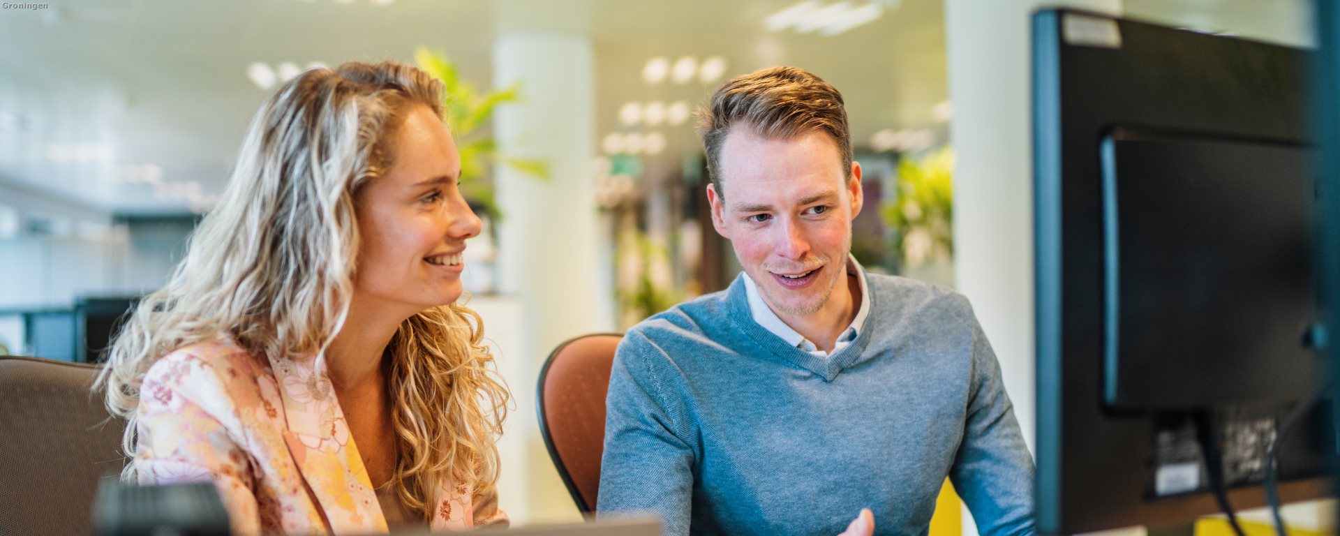 Twee medewerkers achter een bureau kijkend naar een computer