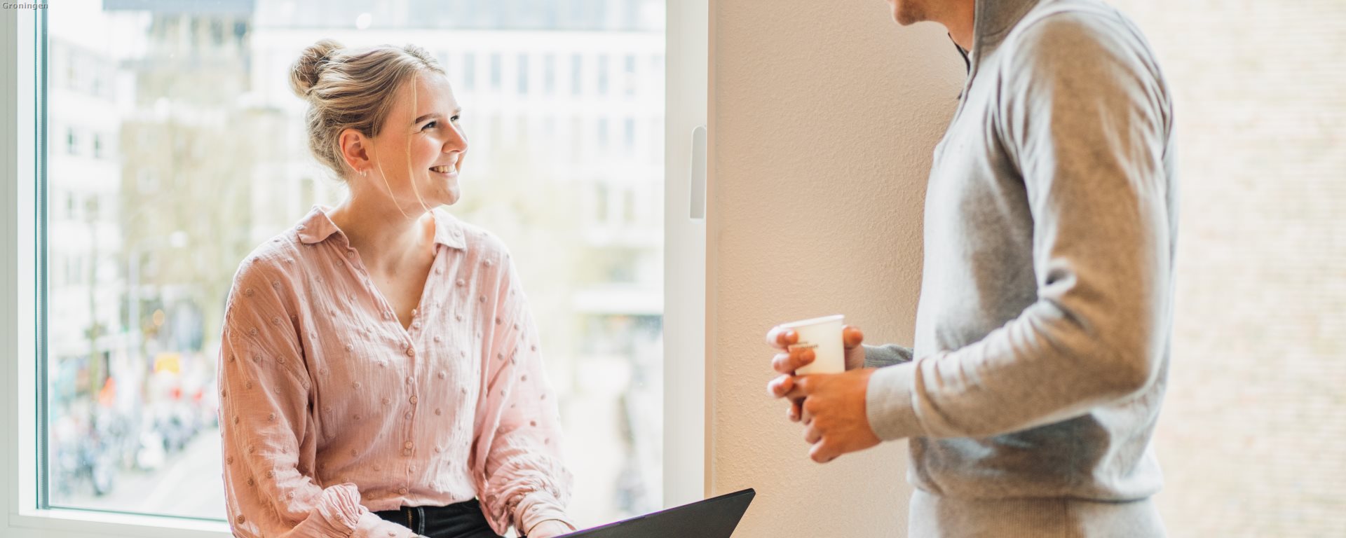 Twee medewerkers bij het raam met een laptop (1)