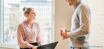 Twee medewerkers bij het raam met een laptop (1)