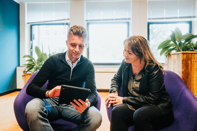 Twee medewerkers kijkend naar een tablet scherm