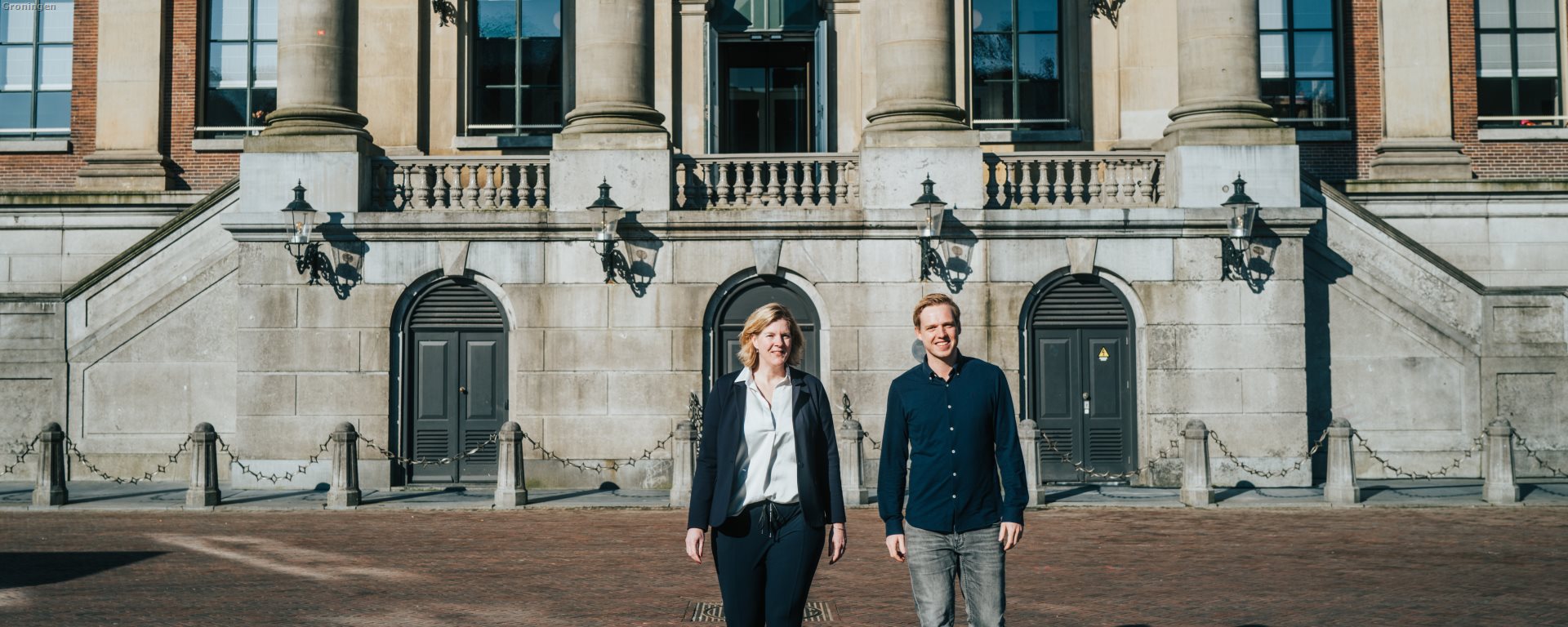 Twee medewerkers lopend voor het stadhuis