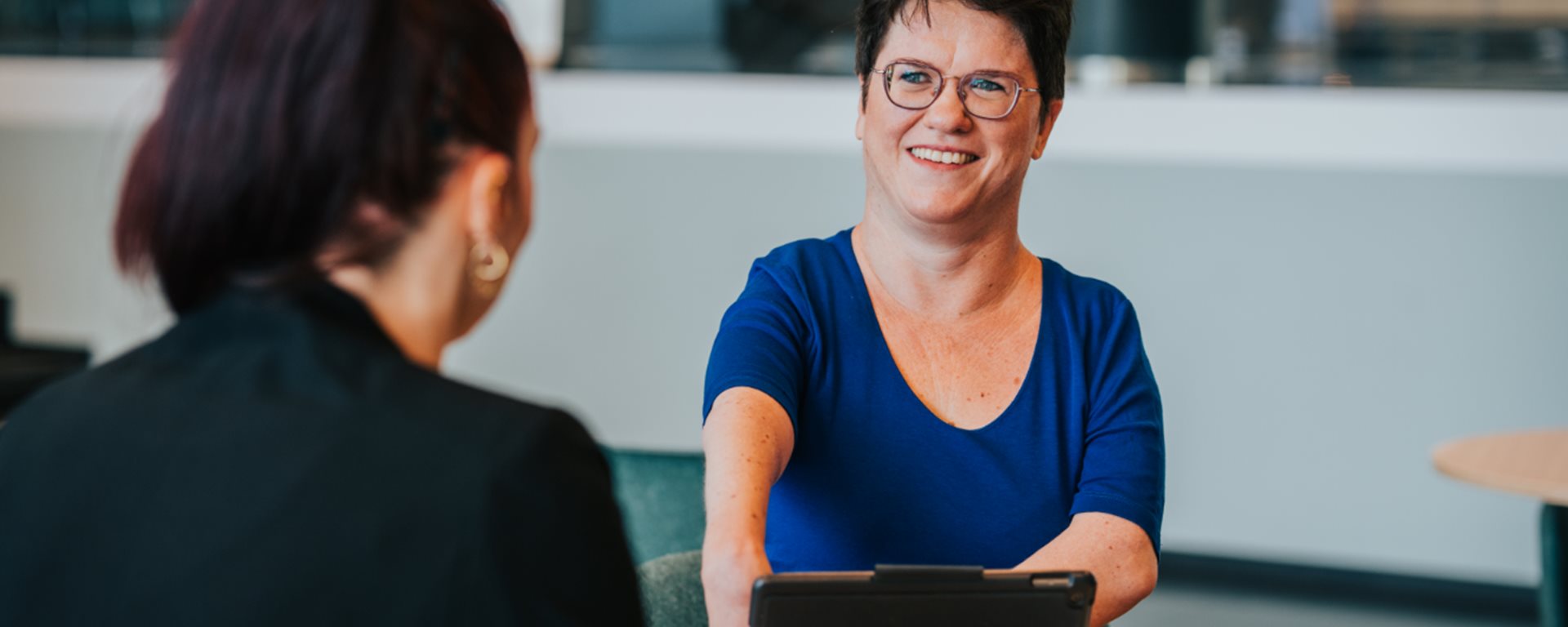 Twee medewerkers op de gemeentelijke locatie op het Harm Buiterplein die aan een tafel zitten