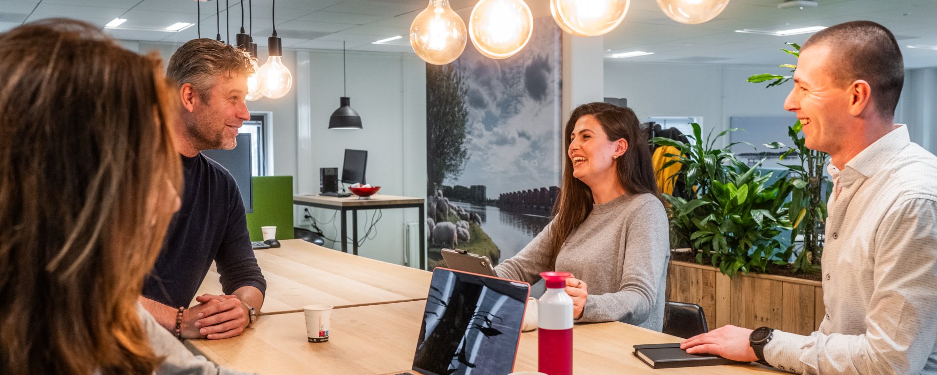 Vier collegas lachend aan tafel