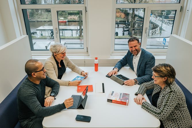 Vier collegas met elkaar in gesprek aan een tafel 