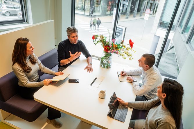 Vier collegas met elkaar in gesprek aan een tafel 