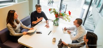 Vier collegas met elkaar in gesprek aan een tafel 3